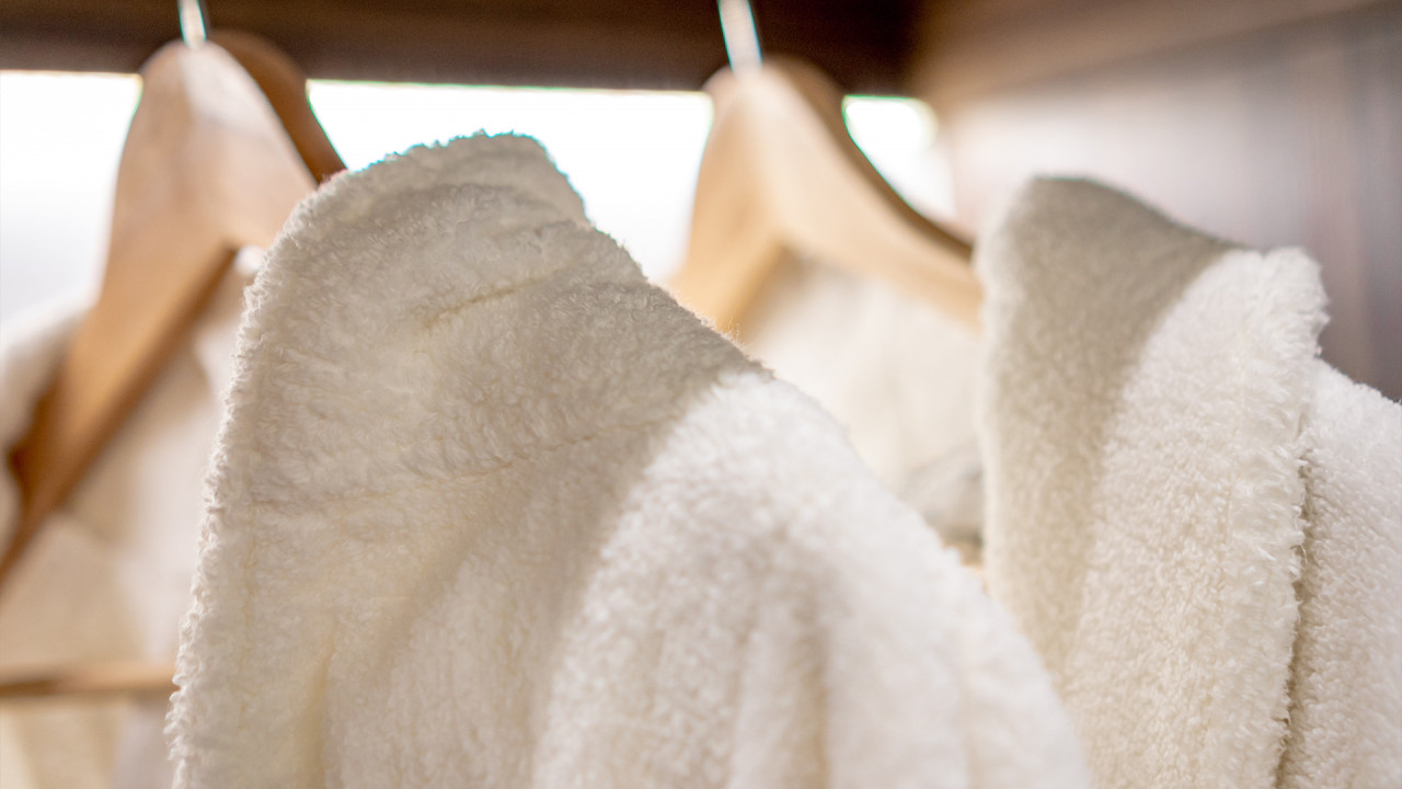 Benen van een vrouw in de sauna met slippers en handdoek op de achtergrond