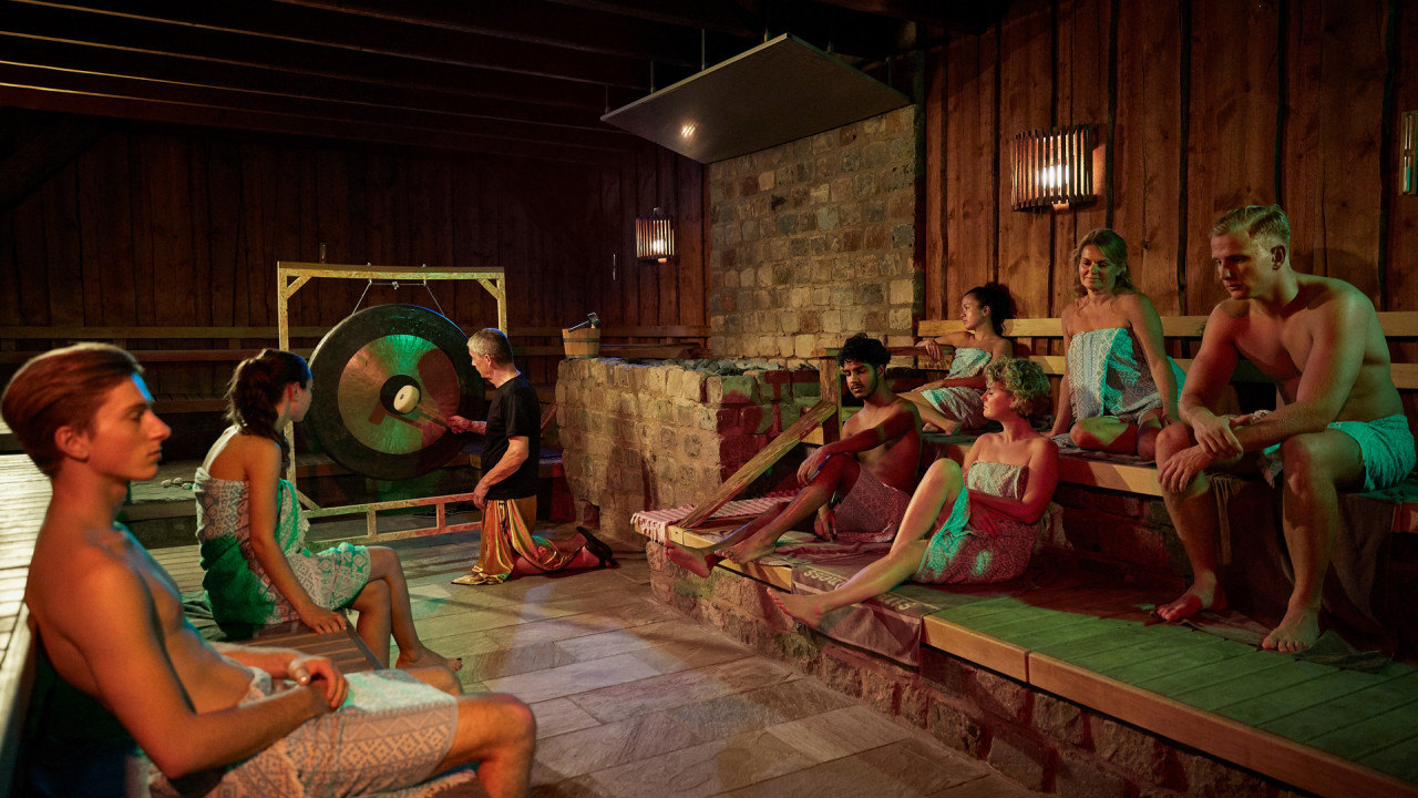 Mensen genieten in een sauna van een wellnessritueel met een gong