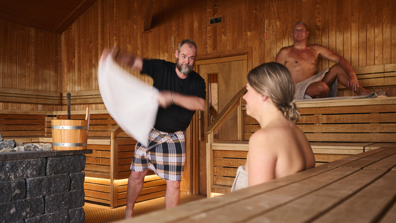 Vrouw geniet van opgieting in sauna