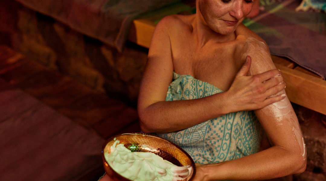 Vrouw brengt lotion aan op haar schouder tijdens wellnessritueel
