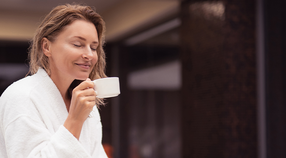 Vrouw in badjas geniet van kop koffie