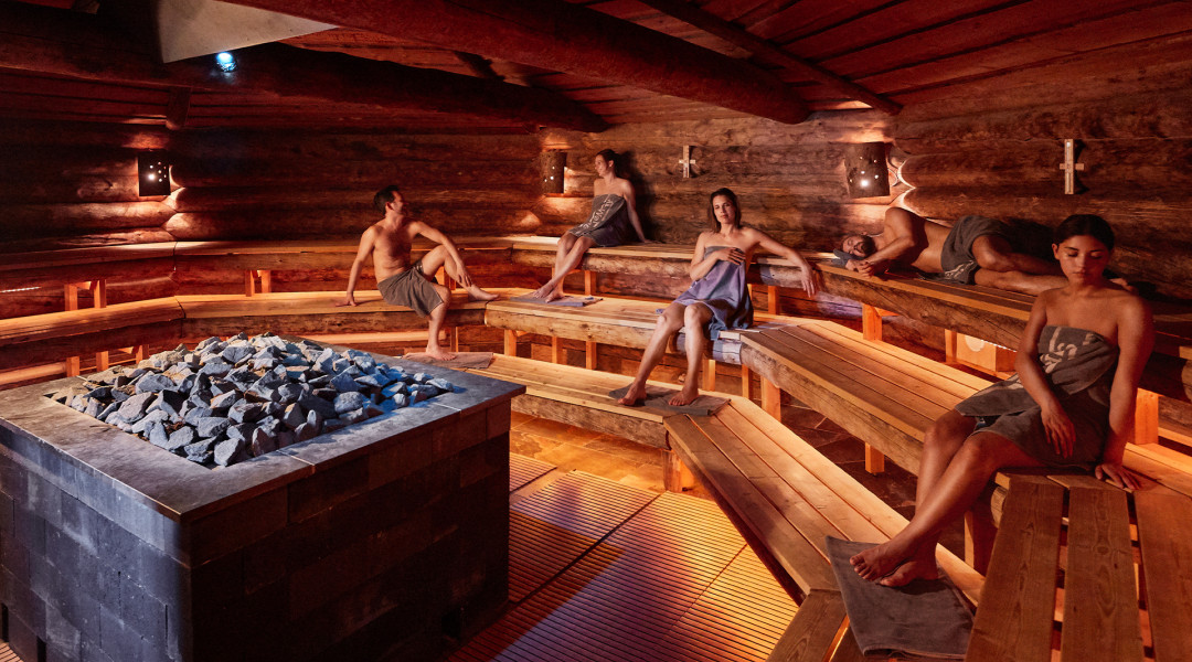 Mensen genieten in sauna met kachel in het midden