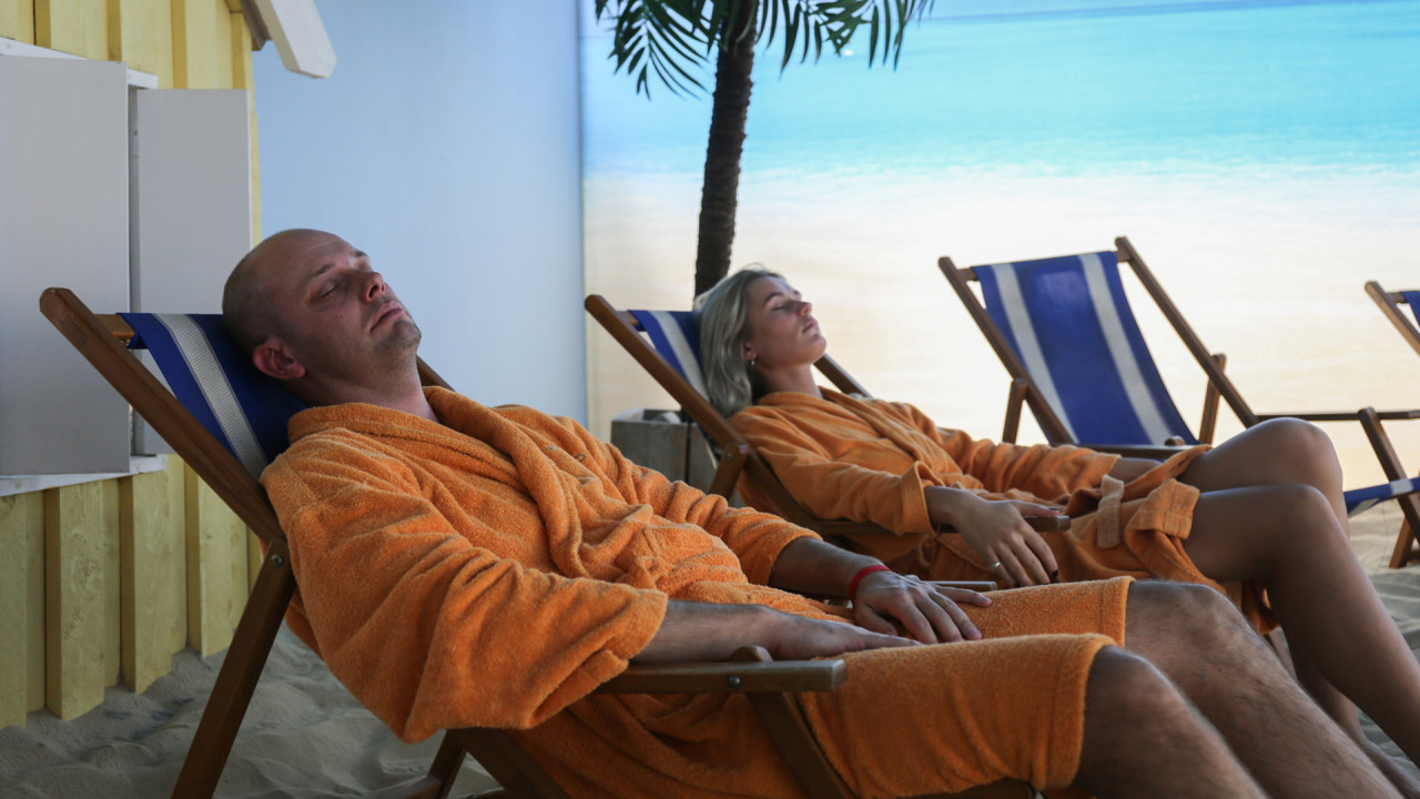 Man en vrouw liggen in ligbed tropisch strand