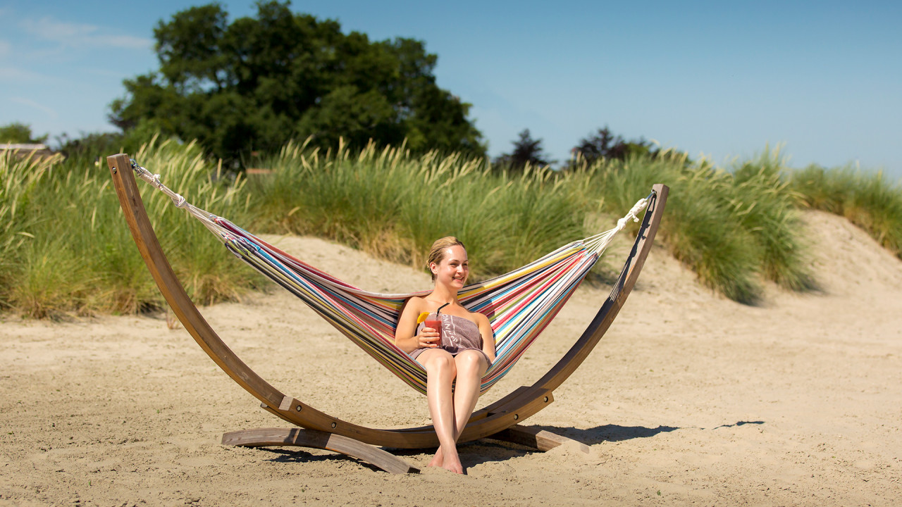Vrouw geniet van de zon in hangmat op het strand van Zwaluwhoeve